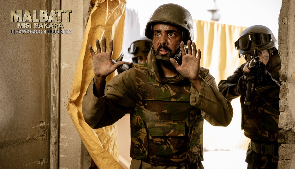 Musa Aden as Abdalle in Malbatt: Misi Bakara, hands raised as soldiers close in behind him